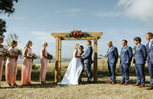 A farm wedding ceremony under a rustic 4-post arbour